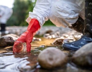 Person in red gloves testing water in a stream