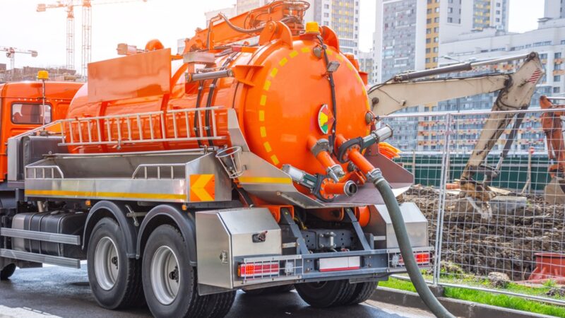 Pumping water from sewage canals during the construction of roads in the city. Truck with orange water tank