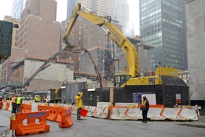 Construction workers and their equipment with “work-in-progress” building project illustrate the active commercial real estate activity in Manhattan.